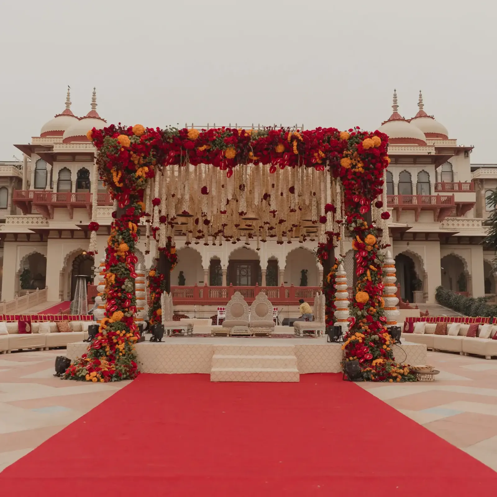Red floral mandap at a palace entrance, designed and produced by DreamzKrraft
